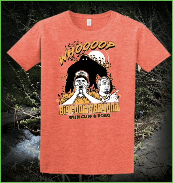 a peach Bigfoot & Beyond shirt displayed with a forest background